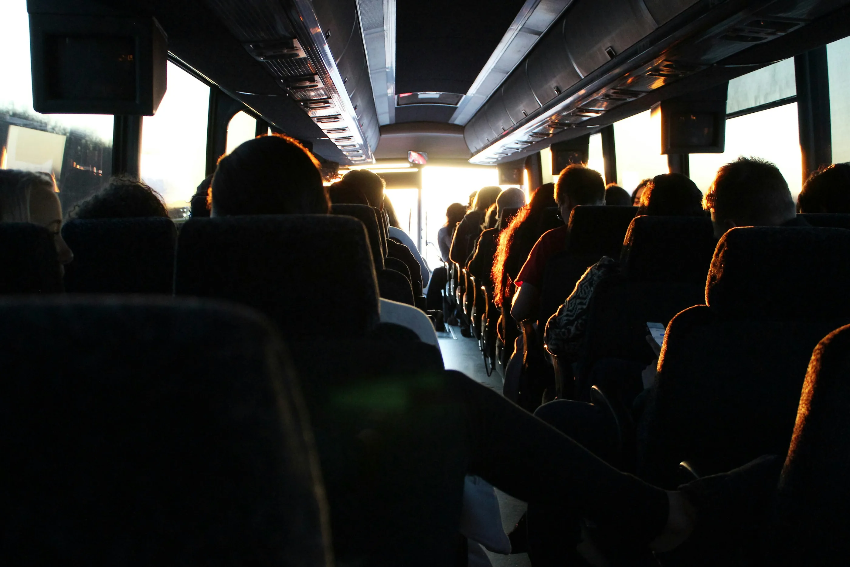 Passengers seated inside a coach as sunlight fills the aisle