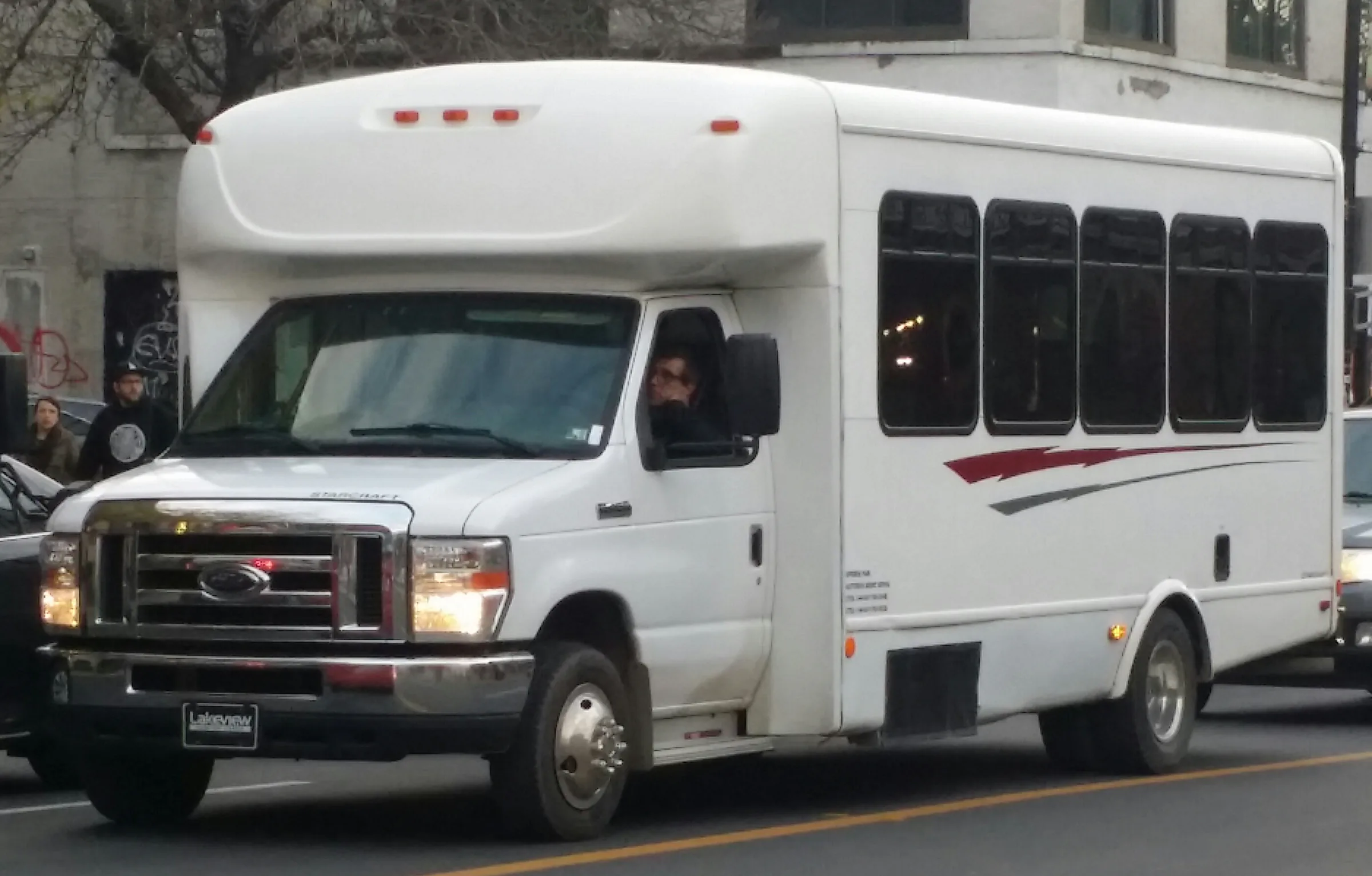 White Ford E-450 cutaway shuttle bus on a city street